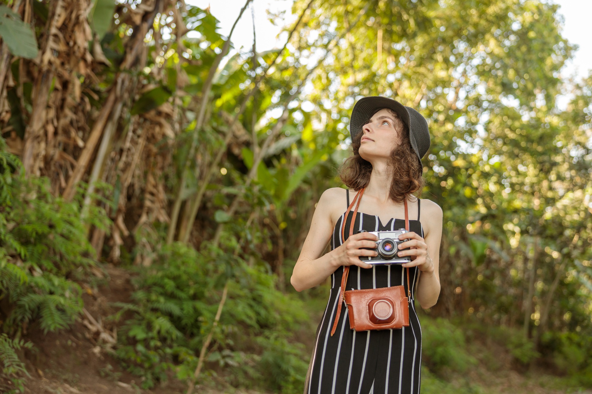 Pretty lady in hat looking at the trees while traveling through Africa
